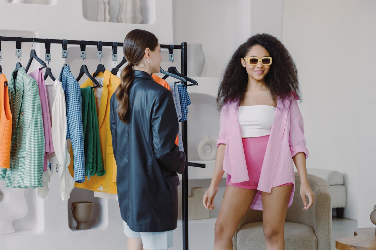 Two women exploring colorful outfits on a rack in a stylish indoor setting.